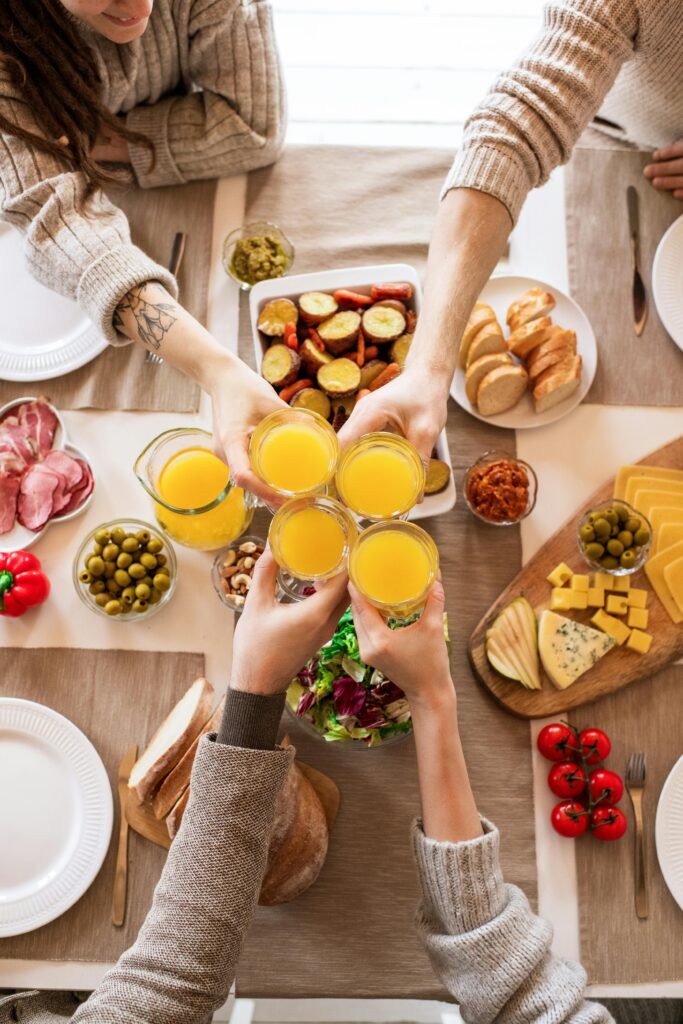 pexels-photo-3756489-3756489 Top view of friends toasting with orange juice during breakfast with a variety of foods.