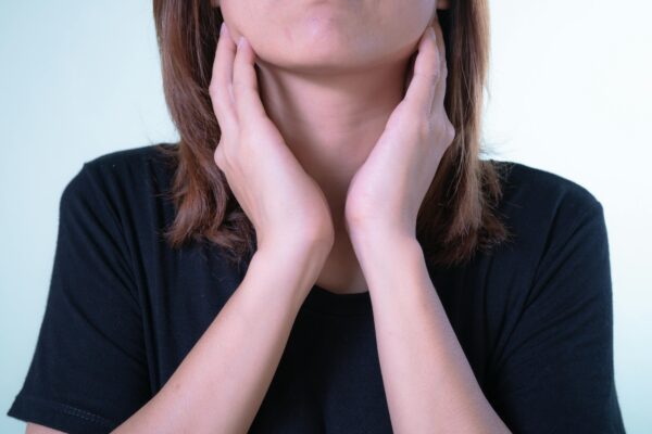 Home Remedies for Sore Throat Close-up of a woman touching her neck, possibly indicating discomfort or throat pain.