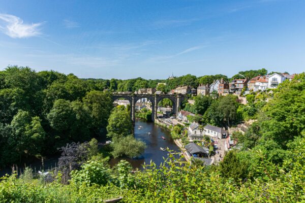 Stunning summer view of Knaresborough, England, featuring a historic viaduct over the River Nidd and lush greenery.