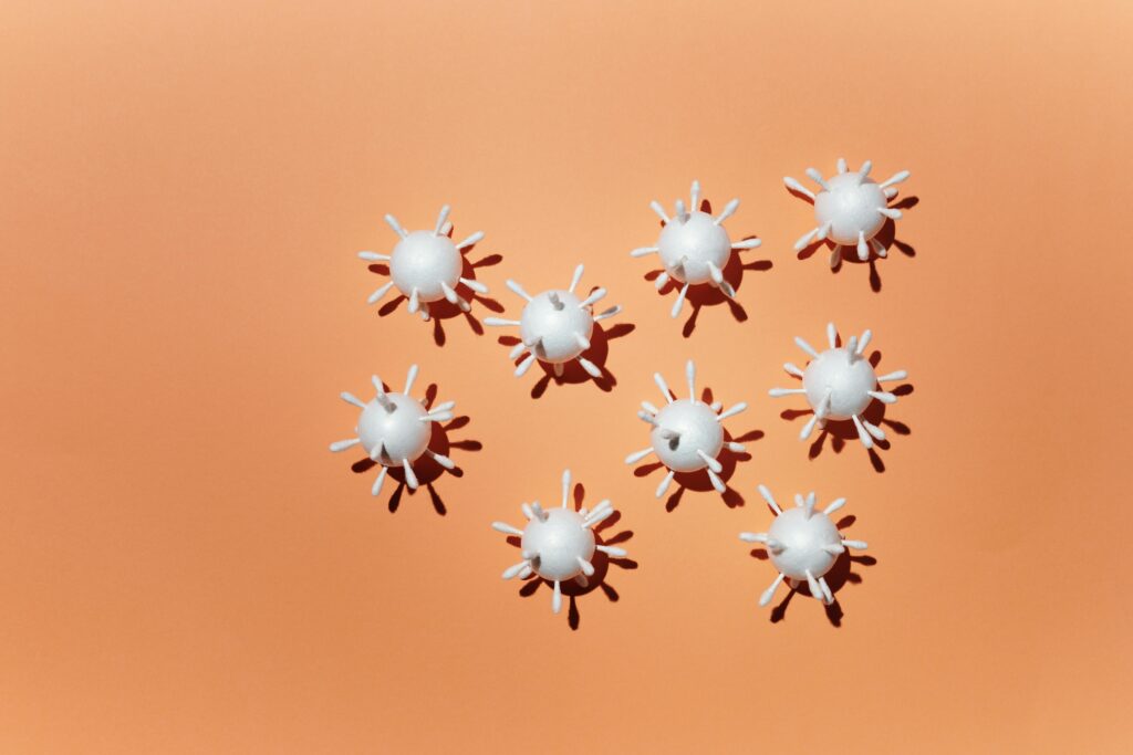 pexels-photo-4031871-4031871 White 3D virus scale models arranged on a peach background, casting shadows.