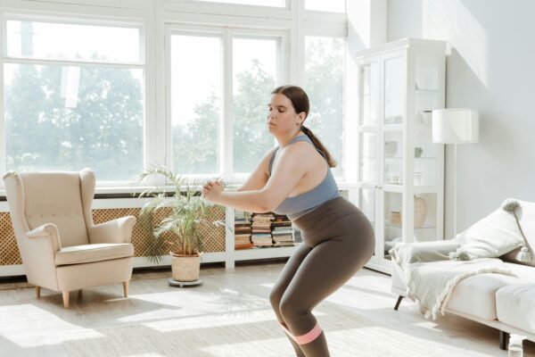 Woman in activewear doing a workout in a sunlit living room, showcasing fitness and health at home.